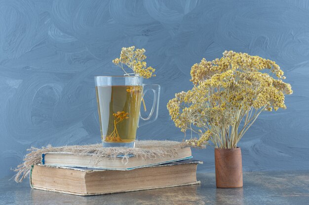 Glas grüner Tee und Blumen auf Buch.