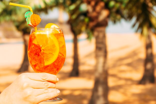 Glas helles Orangensaftgetränk in der Hand