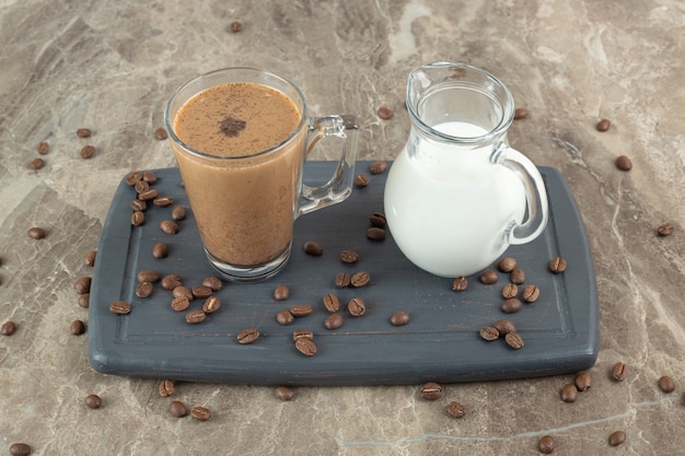 Glas Kaffee und Milch auf dunklem Teller