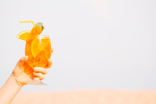 Glas kühlendes Orangensaftgetränk in der Hand