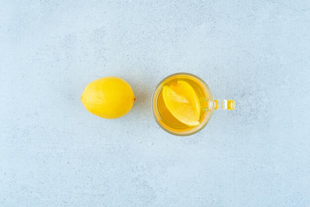 Glas Limonade mit Zitronenscheiben auf blau