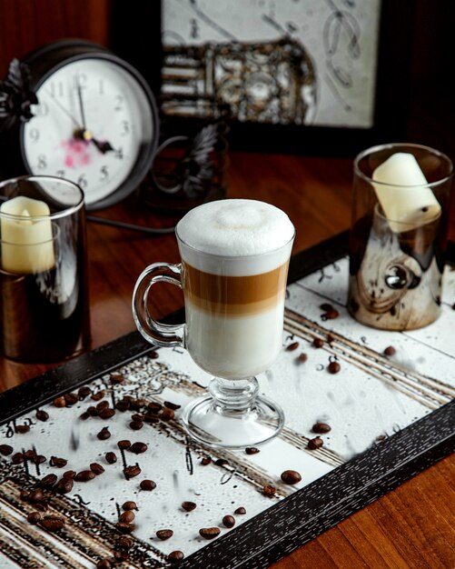 Glas mit Latte und Kaffeebohnen auf dem Tisch