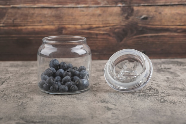 Glas mit leckeren frischen Blaubeeren auf Marmoroberfläche