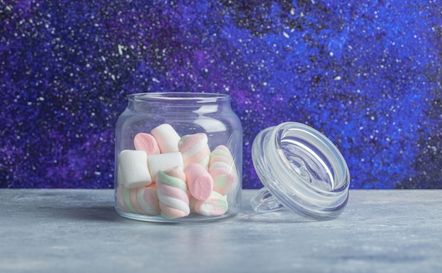 Glas mit weichen bunten Marshmallows auf Marmorhintergrund