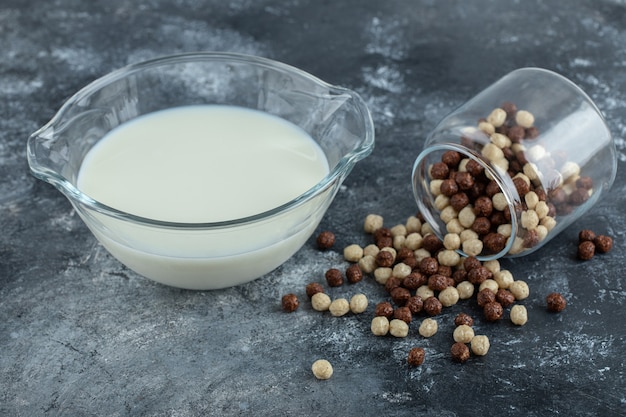 Glas Müslibällchen und Milch auf Marmor.