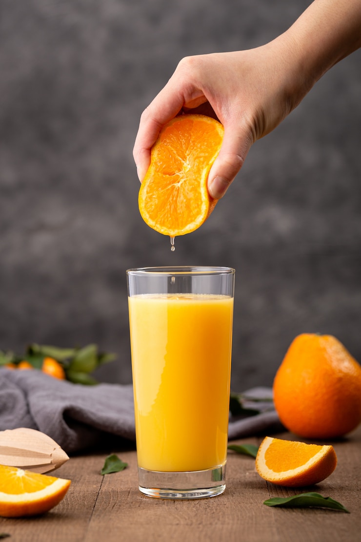 Kostenlose Foto glas orangensaft und eine person, die eine orange darin drückt