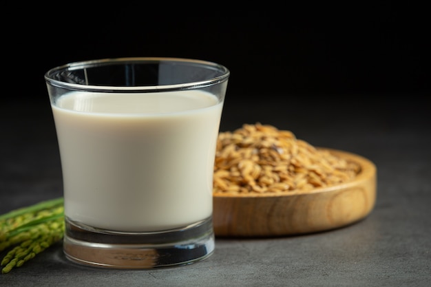 Glas Reismilch mit Reispflanze und Reissamen auf dunklen Boden gestellt