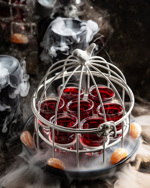 Glas Schüsse mit rotem Getränk in Kuchen in der geräucherten Pfanne