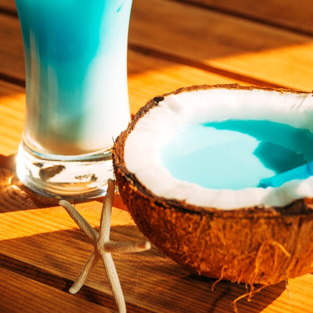 Glas und gebrochene Kokosnuss mit hellem blauem Getränk