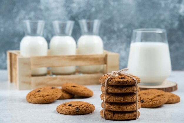 Glas und Glas Milch mit Stapel Keksen auf Marmortisch.