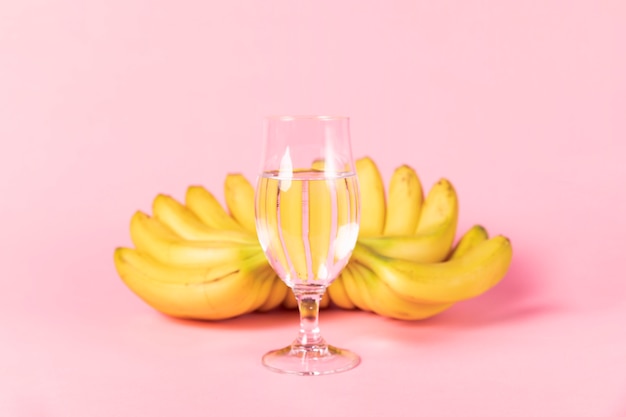 Glas Wasser mit Bananen im Hintergrund