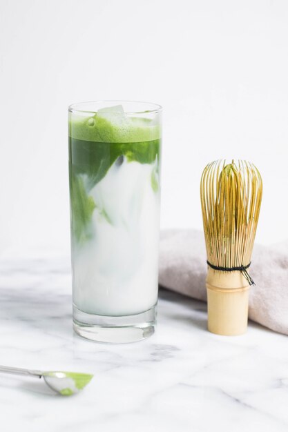 Glas Wasser mit Gemüseblättern auf einer weißen Oberfläche