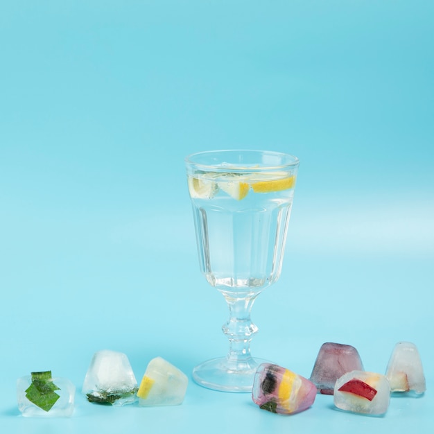 Glas Wasser mit Zitrone mit Eiswürfeln auf blauem backgrounes