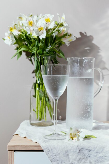 Glas Wasser und Vase mit Blumen