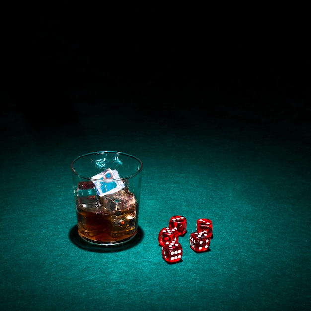 Kostenloses Foto glas whisky und rote würfel auf grüner kasinotabelle