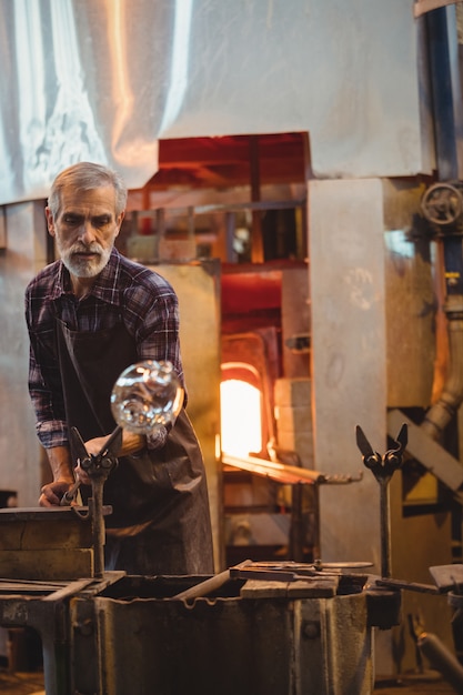 Kostenloses Foto glasbläser, der ein geschmolzenes glas formt