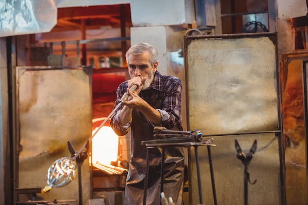 Glasbläser, der ein Glas auf dem Blasrohr formt