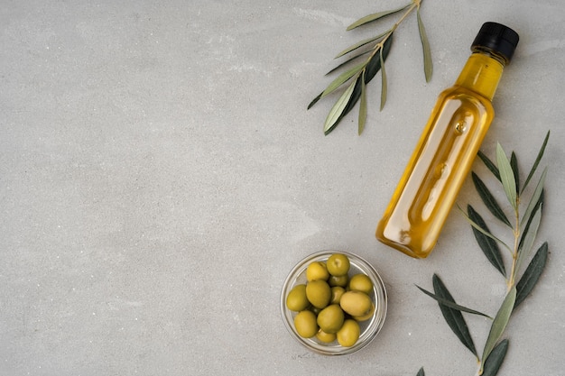 Glasflasche mit Olivenöl auf grauem Hintergrund