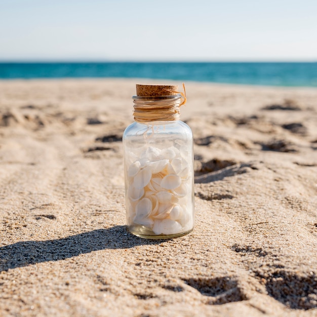 Glasglas mit Muscheln auf Sand