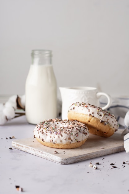 Glasierte Donuts mit Streuseln und Milchflasche