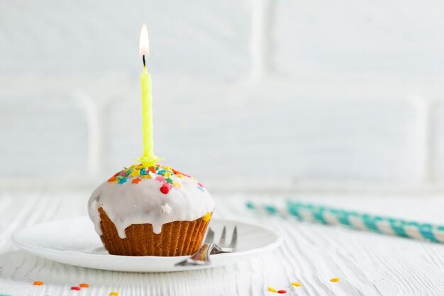 Glasierter kleiner Kuchen mit brennender Kerze