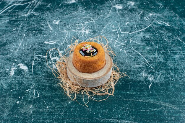 Glasierter Minikuchen auf einem Brett, auf blauem Hintergrund. Foto in hoher Qualität