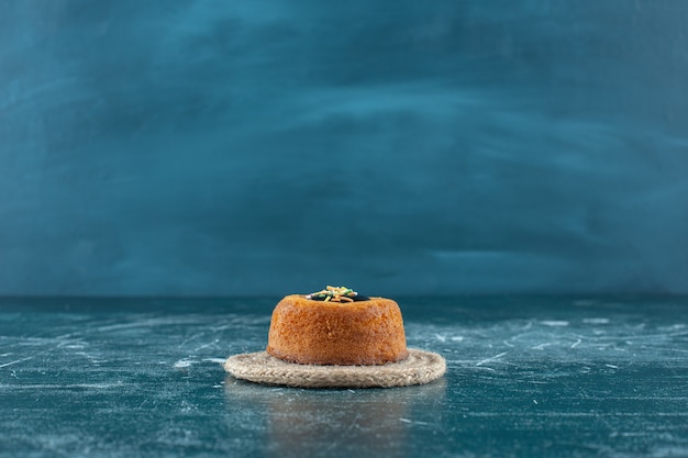 Glasierter Minikuchen auf einem Untersetzer, auf blauem Hintergrund. Foto in hoher Qualität