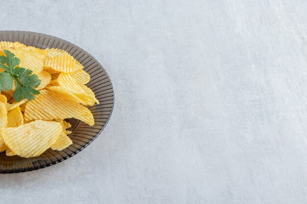 Glasplatte mit leckeren Ripple-Chips auf Stein.