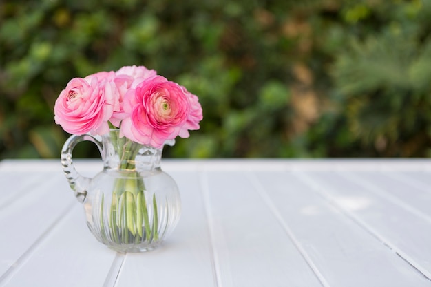 Glasvase mit Blumen in rosa Tönen