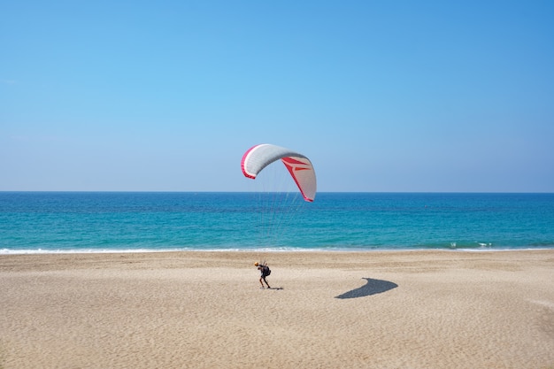 Gleitschirm fliegt über die Küste mit blauem Wasser und Himmel auf Horison. Ansicht des Gleitschirms und der blauen Lagune in der Türkei.