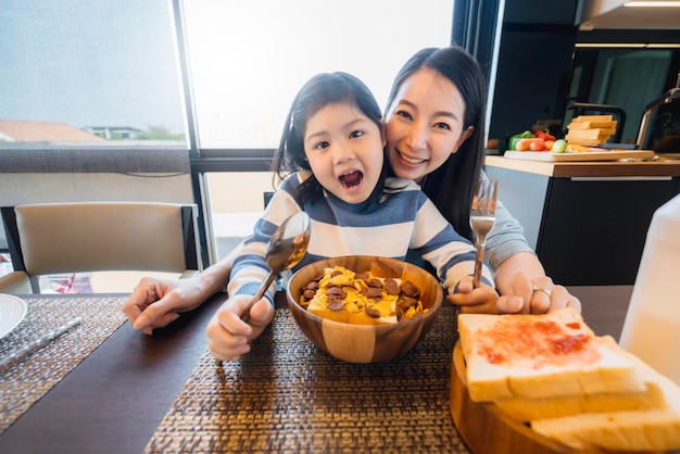 Glück asiatische mutter und tochter genießen müslifrühstückszeit gesundes lebensmittelkonzept esszimmerhintergrund