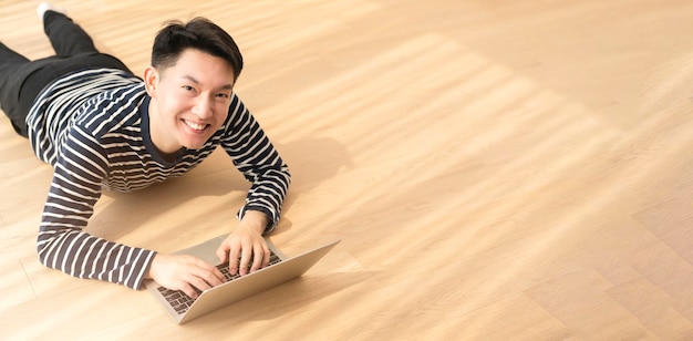 Glück, friedliches Lächeln, asiatischer Mann, genießen Sie die Arbeit von zu Hause aus, Quarantäne, entspannen Sie sich und arbeiten Sie positiv mit dem Laptop