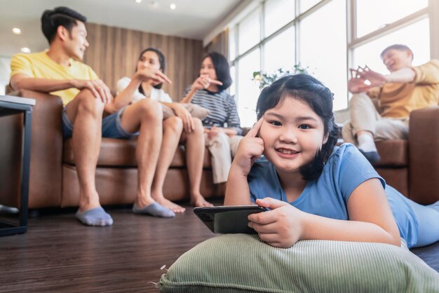 Glück fröhliches asiatisches tochterkind, das sich auf den boden legt, blick in die kamera mit zahnigem lächeln im wohnzimmer, während ihre familie große eltern zusammen mit liebe und karrierischer familie zu hause besucht