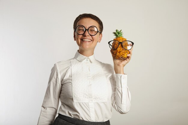 Glücklich aussehender verrückter Lehrer mit einer Ananas in passenden Gläsern lokalisiert auf Weiß