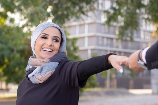 Glücklich lächelnde arabische Frau. Porträt einer Frau mit bedecktem Kopf und Make-up, die ihren Freund mit strahlendem Lächeln ansieht. Internationales, schönes Konzept