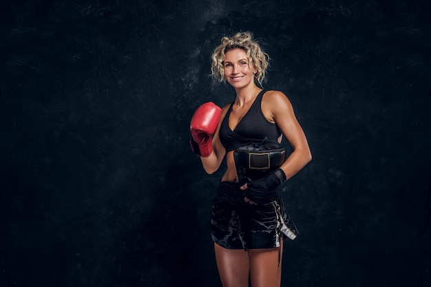 Kostenloses Foto glücklich lächelnde boxerin posiert für fotografen im dunklen fotostudio.