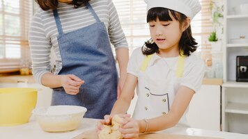 Glücklich lächelnde junge asiatische japanische familie mit vorschulkindern hat spaß beim backen von gebäck past