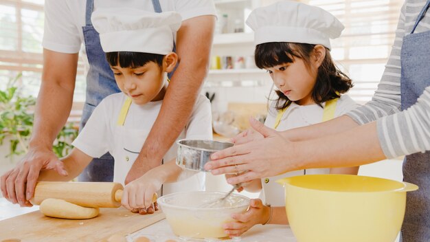 Glücklich lächelnde junge asiatische japanische Familie mit Vorschulkindern hat Spaß beim Backen von Gebäck past