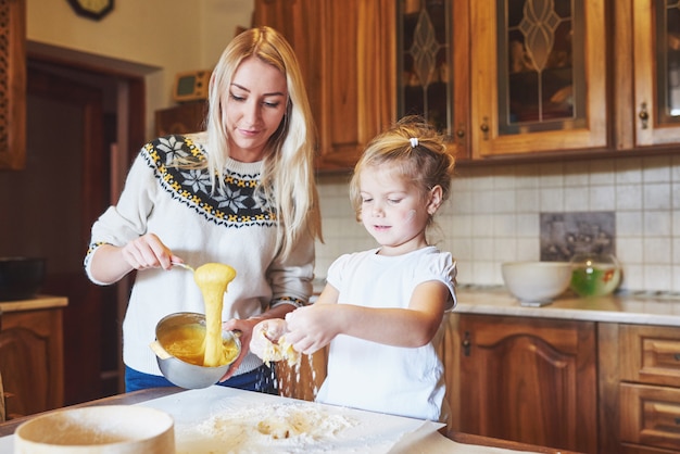Glücklich lächelnde Mutter in der Küche backt Kekse mit ihrer Tochter.