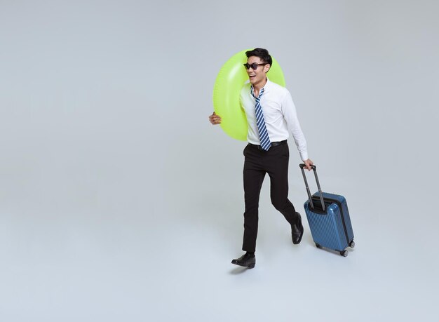 Glücklich lächelnder asiatischer Geschäftsmann mit Koffer und Gummiring, der ihren Sommerurlaub genießt