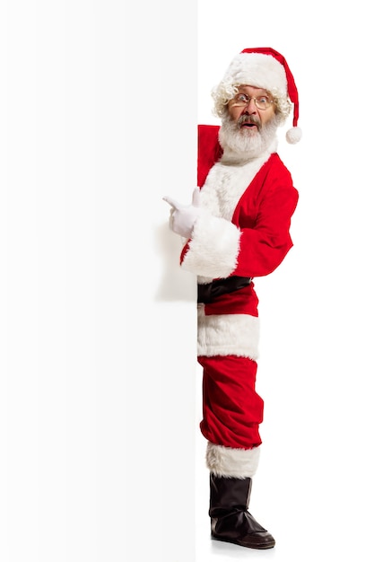 Glücklich überrascht Weihnachtsmann zeigt auf leere Werbewand mit Kopierraum
