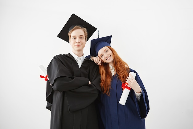 Glückliche Absolventen der Universität lächeln, die holsing Diplome aufwerfen.