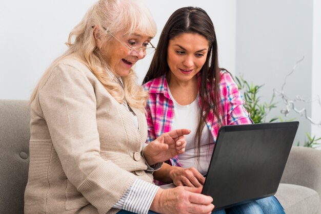 Glückliche ältere Mutter und Tochter, die Laptop betrachtet