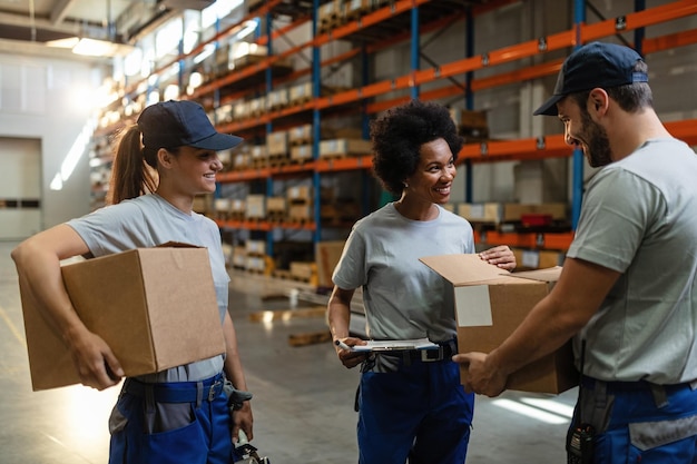 Glückliche Afroamerikanerin und ihre Kollegen untersuchen Pakete, während sie im Auslieferungslager arbeiten