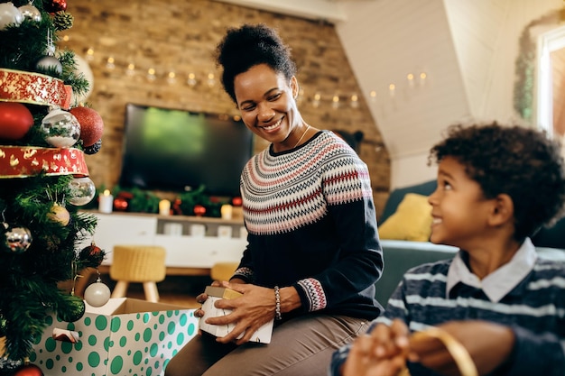 Glückliche afroamerikanische Mutter, die mit ihrem Sohn spricht, während sie das Haus zu Weihnachten dekoriert