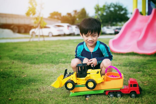 Glückliche asiatische Kinder, die auf dem Rasen im Spielplatz spielen