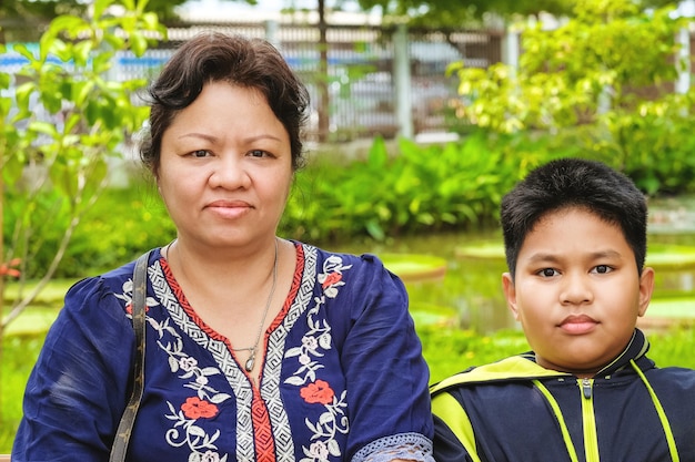 Glückliche asiatische Mutter, die mit ihrem Sohn sitzt und im Park sitzt