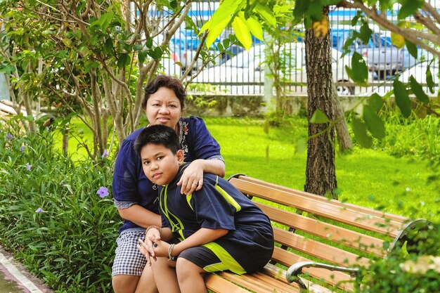 Glückliche asiatische Mutter, die mit ihrem Sohn sitzt und im Park sitzt