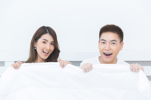 Glückliche asiatische Paare auf dem Bett zu Hause