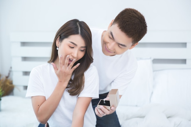 Glückliche asiatische Paare auf dem Bett zu Hause